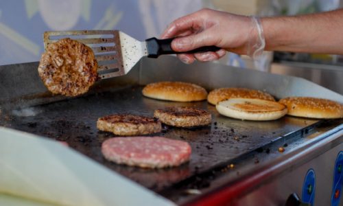 Person flipping hamburgers on a grill