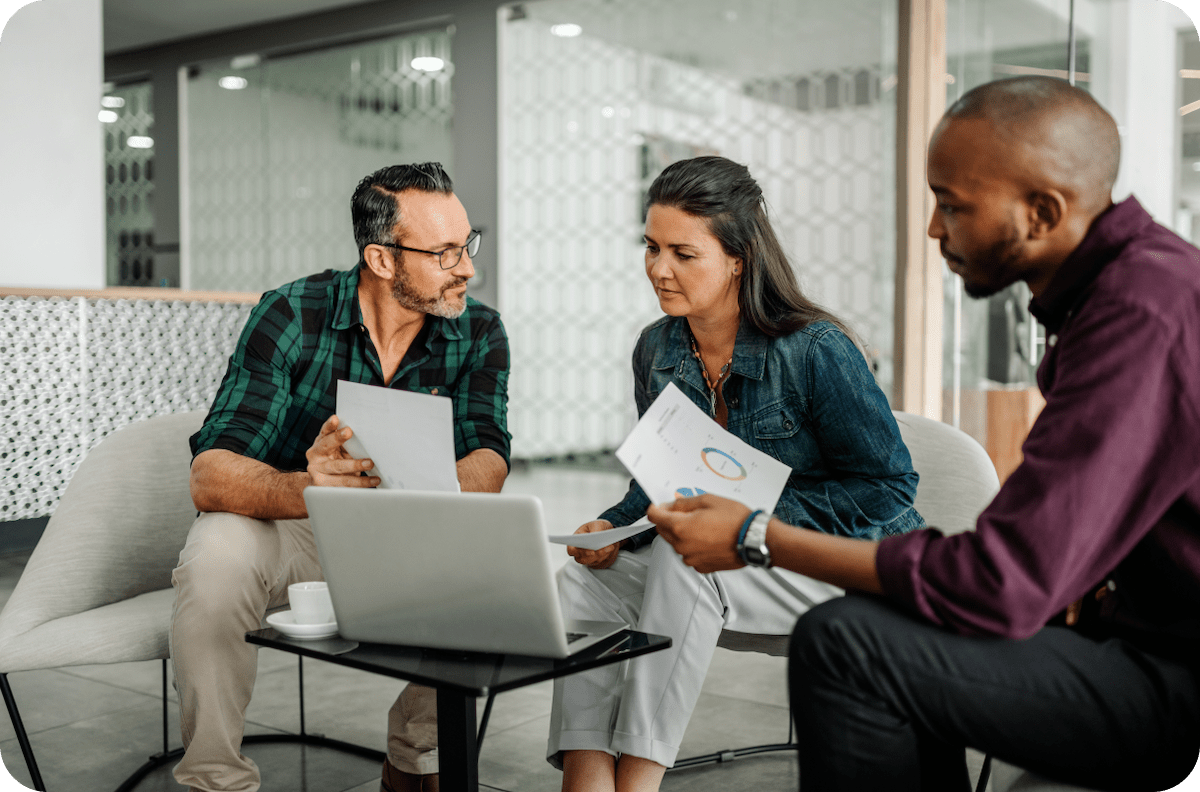 3 people review financial documents on the couch in the office