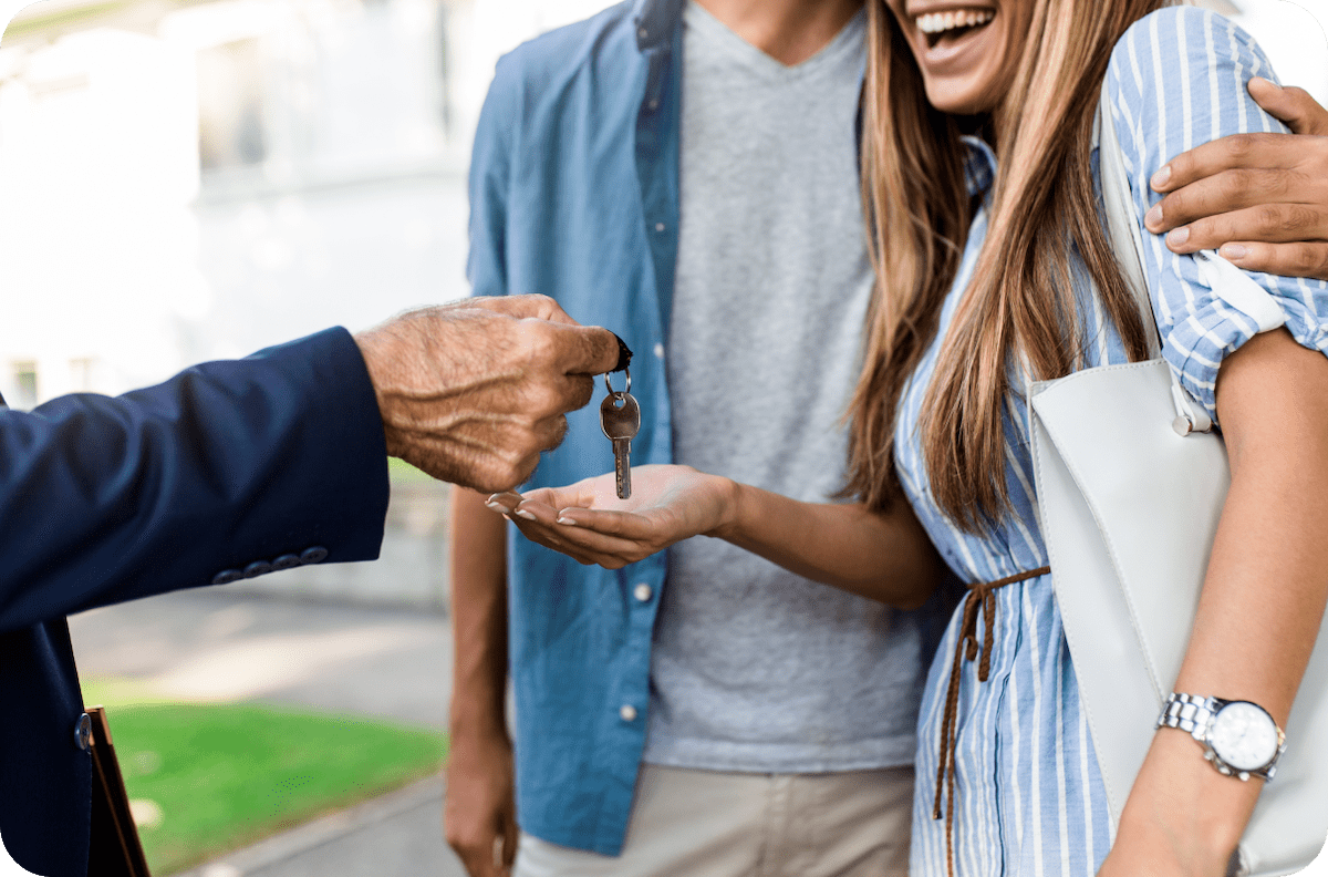 A man handing a couple a key to their new home