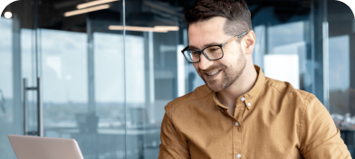 A man in glasses smiles at his computer