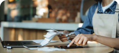 A person in an apron counts receipts