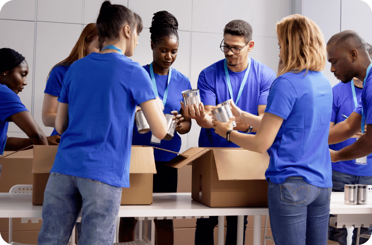 A team of people in blue shirts pack boxes together
