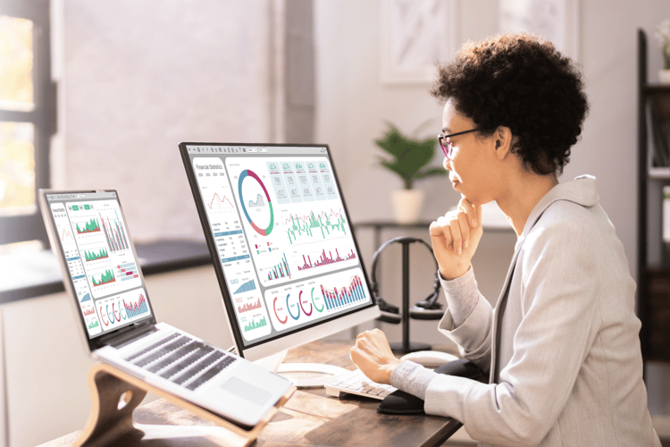 woman looking at computer with financial growth charts on screen