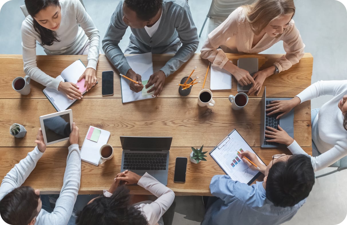 8 colleagues working together on a large wooden table in an office