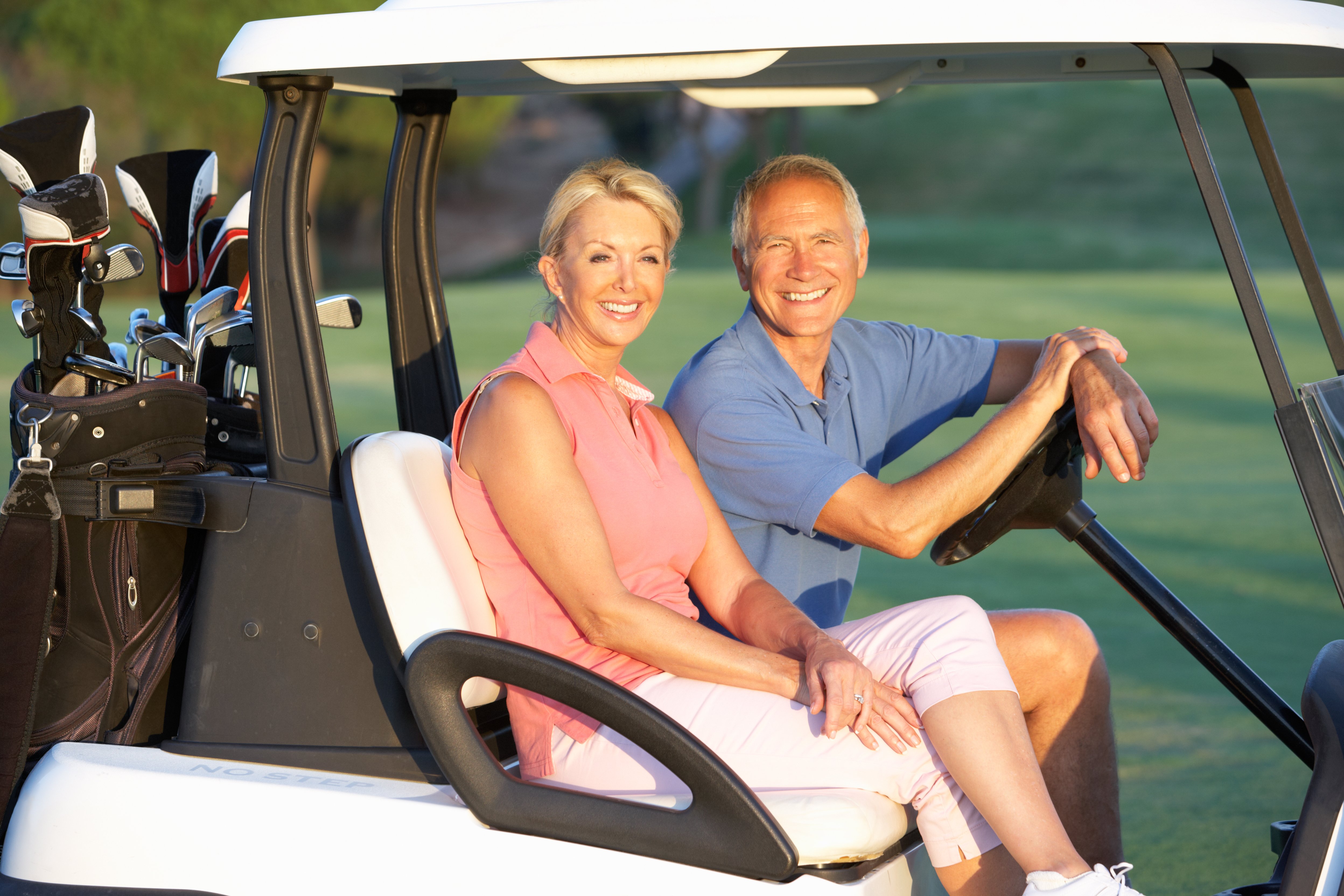 elderly couple riding a golf cart