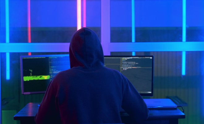 A hooded cyber attacker attempting to infiltrate cybersecurity measures on a computer | Varay Managed IT, San Antonio & El Paso