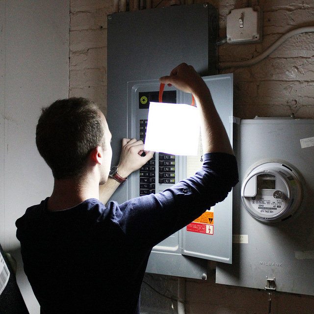 Man using light in dark to check power.