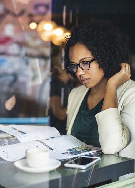 woman sitting at a coffee shop table reading the news