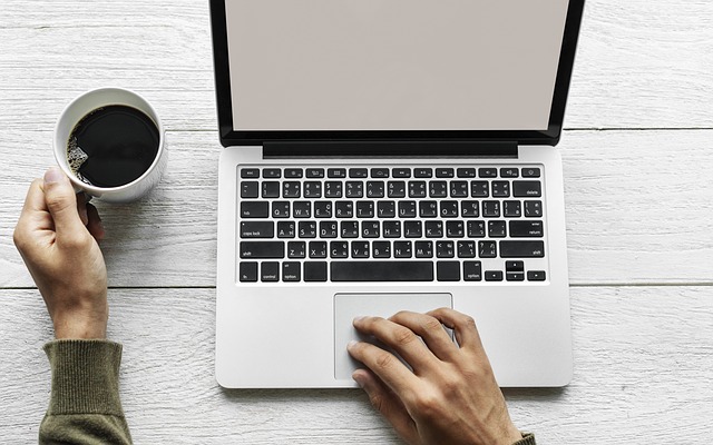 person working on laptop with coffee cup 