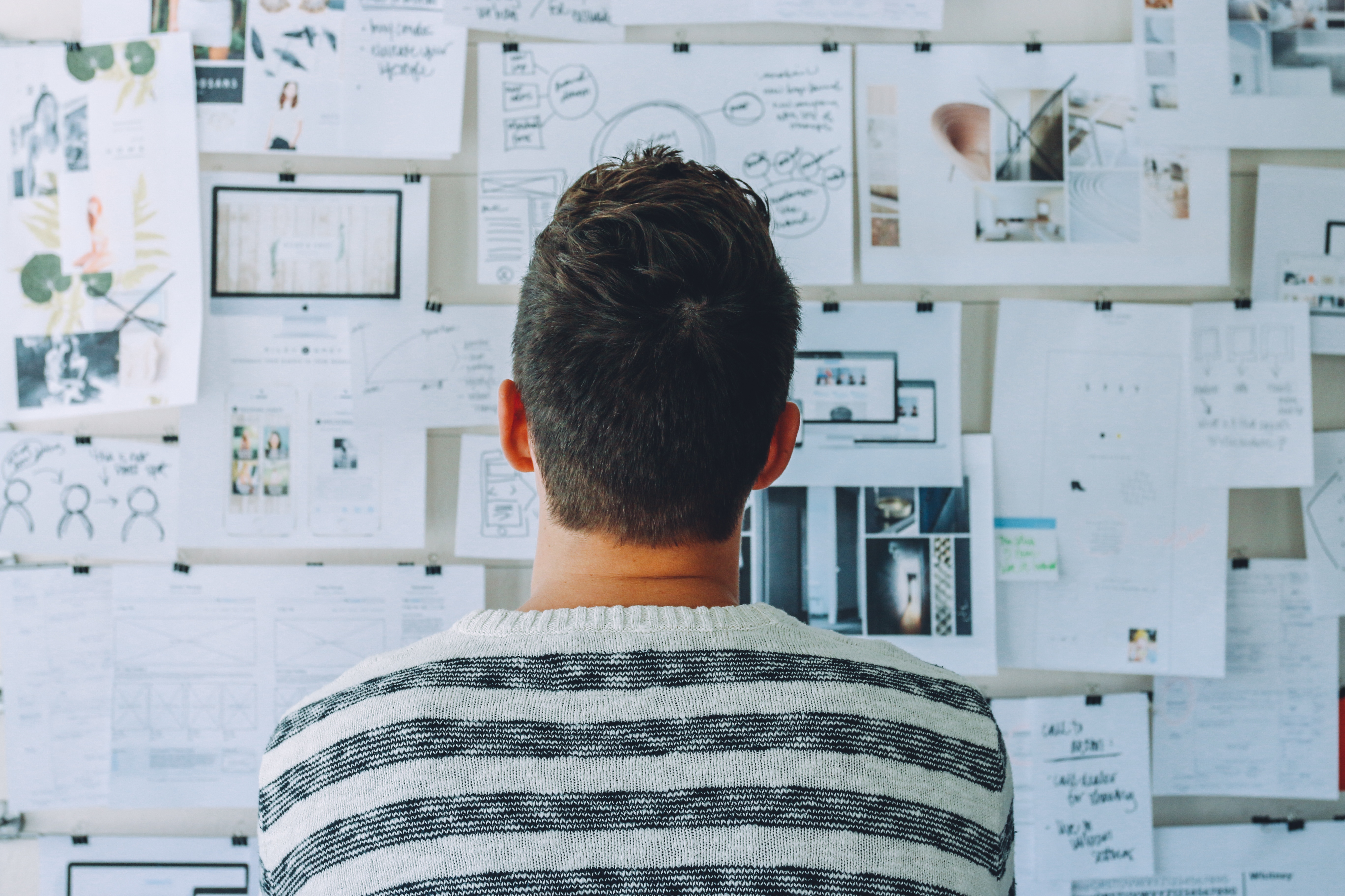 Man staring at a wall of materials as he creates a business plan