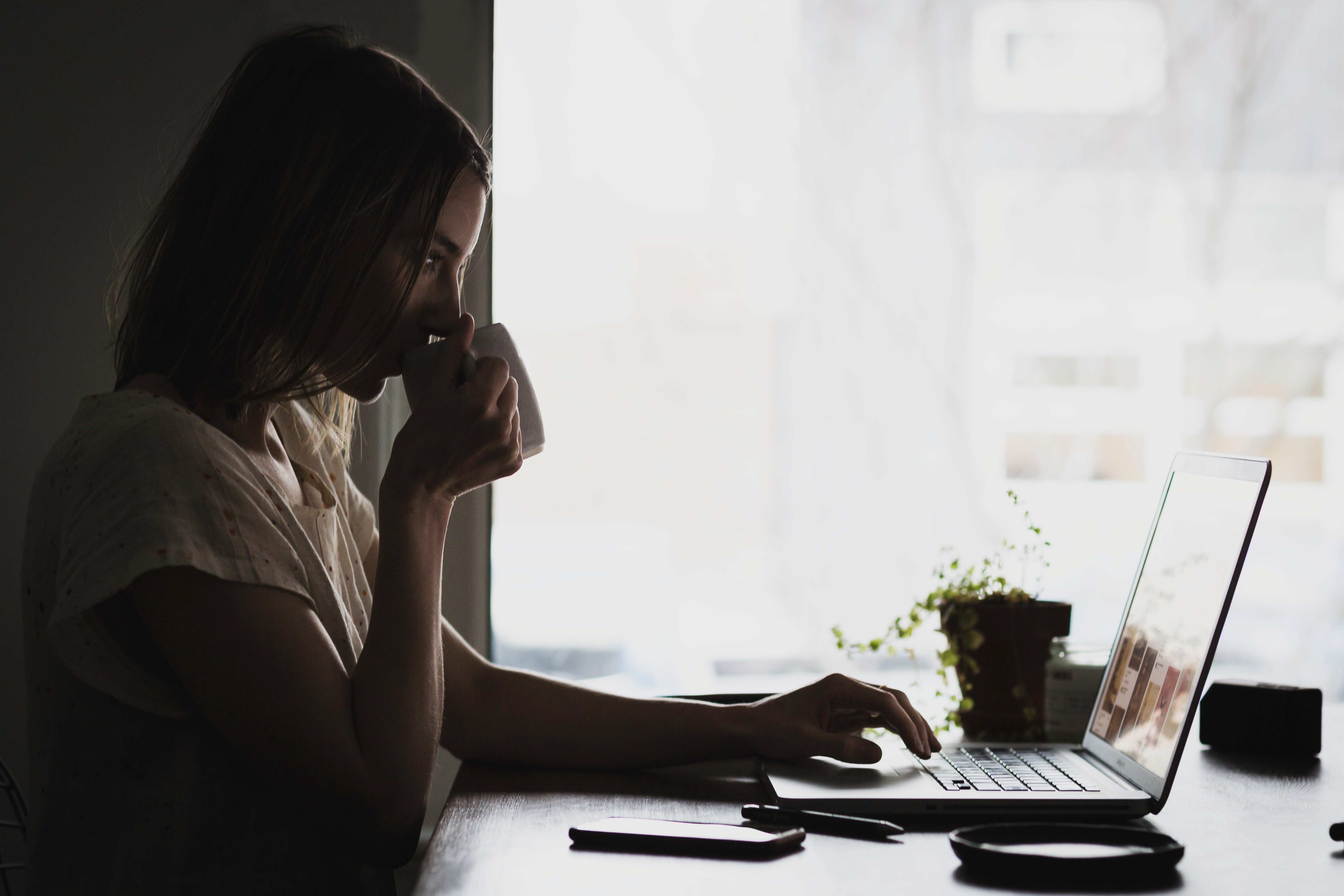 woman drinking coffee at a computer