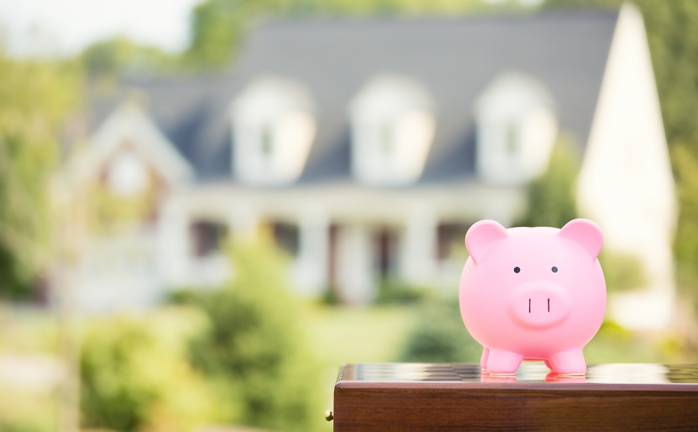 Real estate sale, home savings, loans market concept. Housing industry mortgage plan and residential tax saving strategy. Piggy bank isolated outside home on background. Focus on piggybank. Homeowner.jpeg