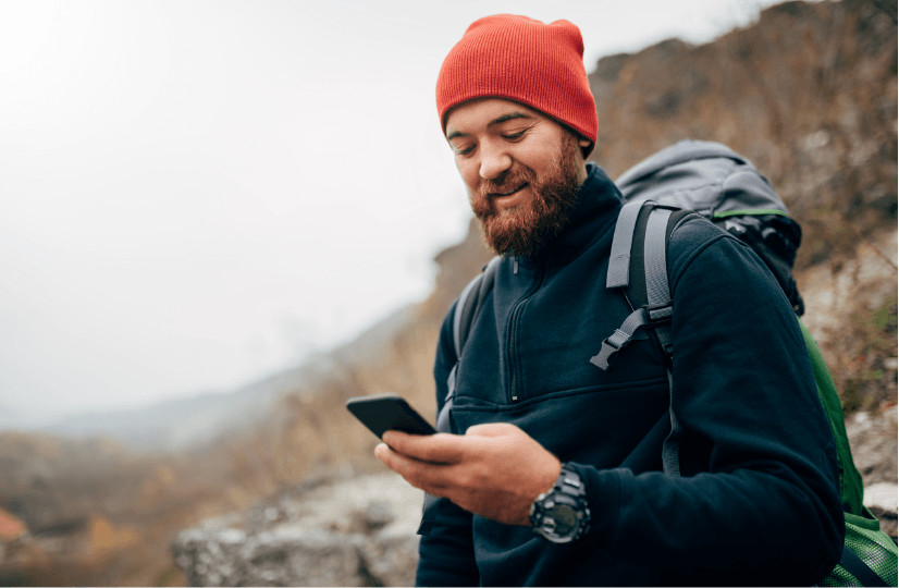 Young Man on Smartphone While Hiking in Fall