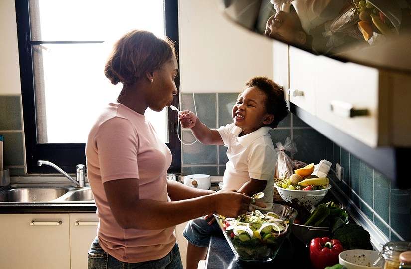 child feeding mother in kitchen