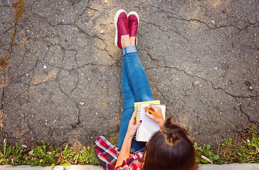 Student Sitting on Curb Writing Notes