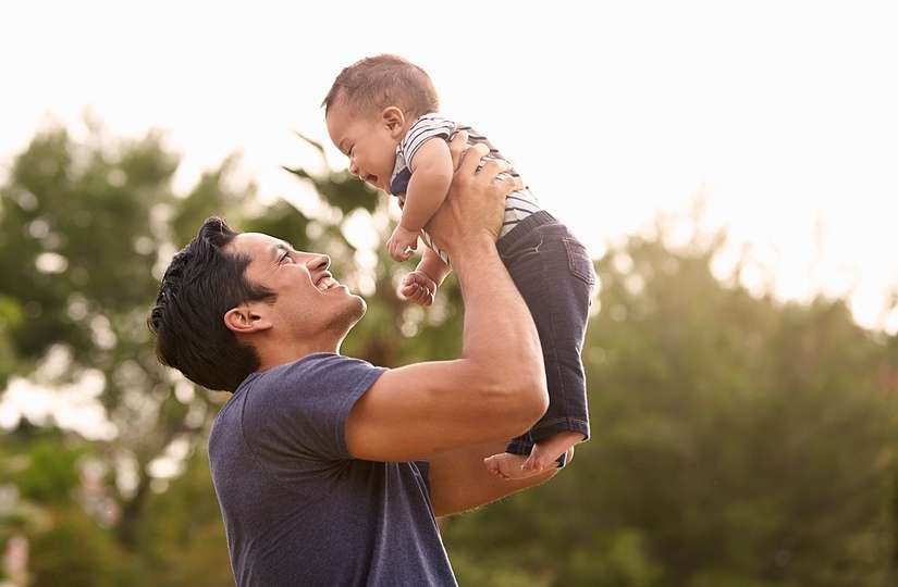 young dad holding son in air