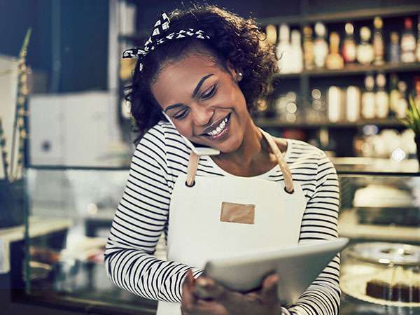 business owner talking on phone while on tablet