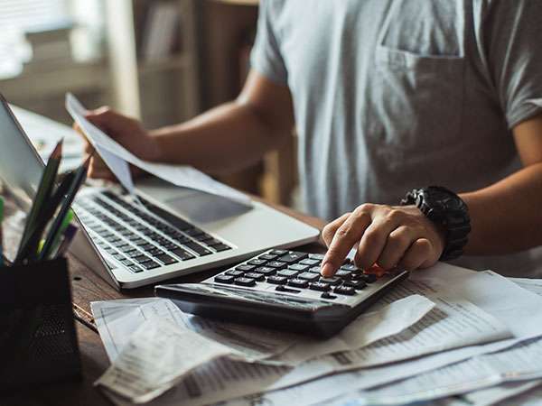 man budgeting with calculator and laptop