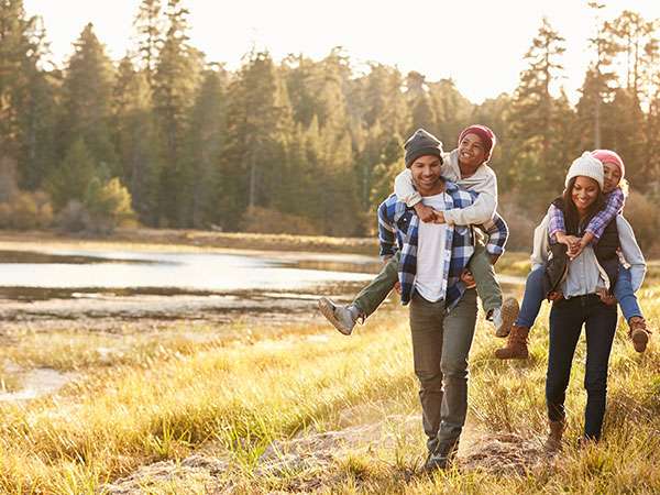 mom and dad with children riding piggyback by lake