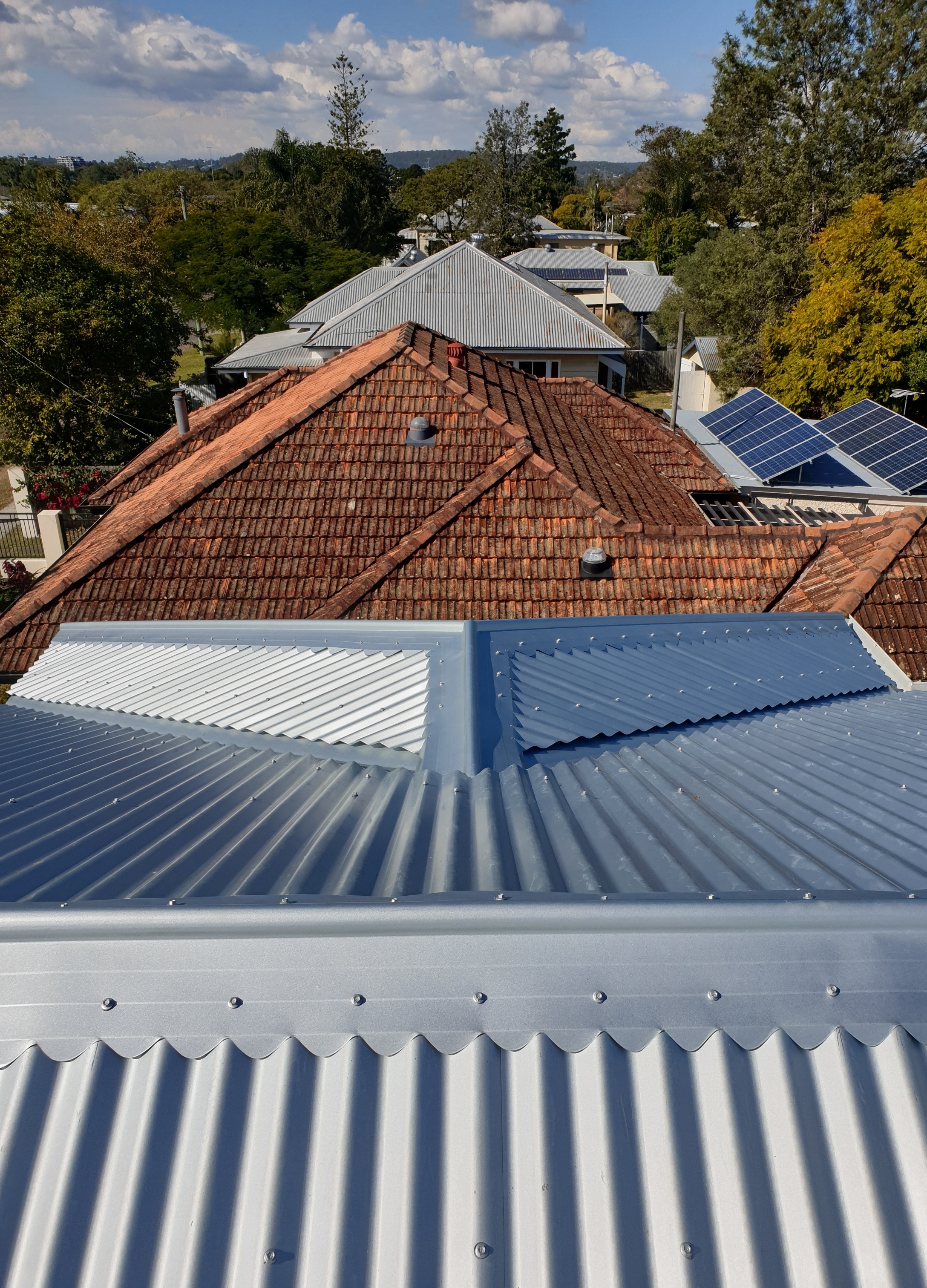New metal roof with old tile roof in background