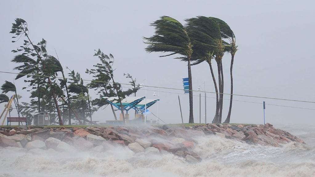 High winds drive surf onto land, trees blowing