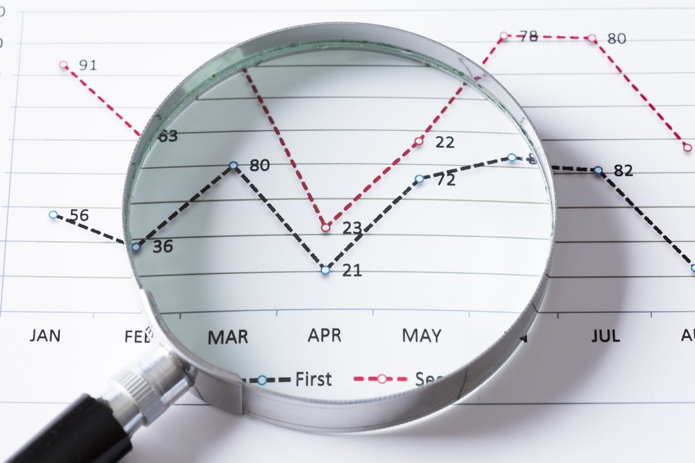 Magnifing glass and documents with analytics data lying on table .jpeg