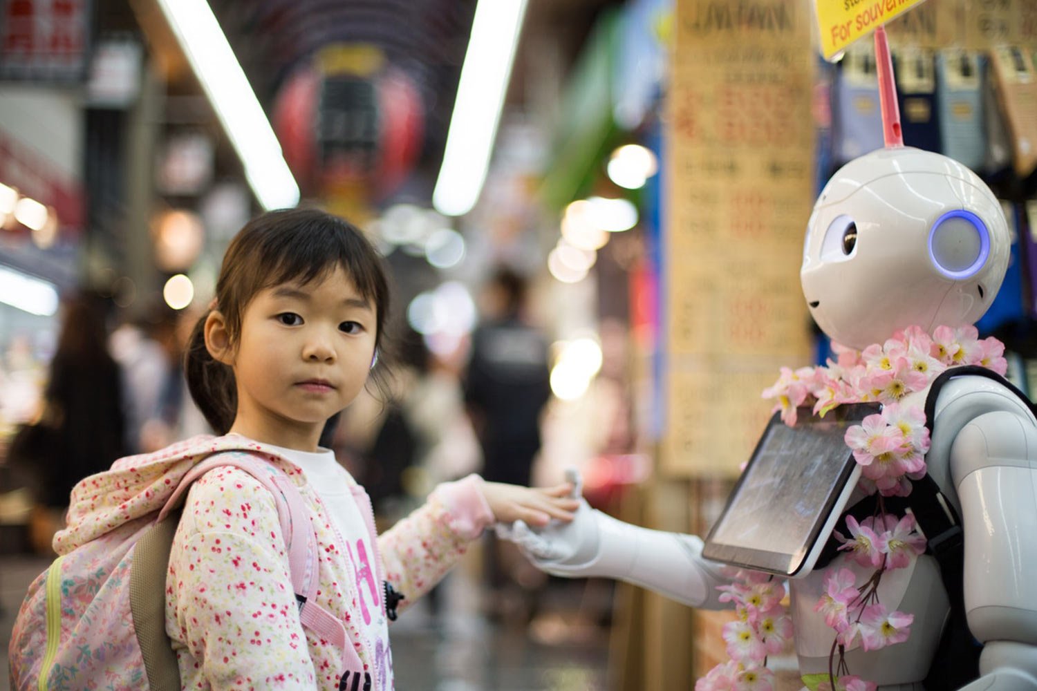 Small child holding hands with a robot