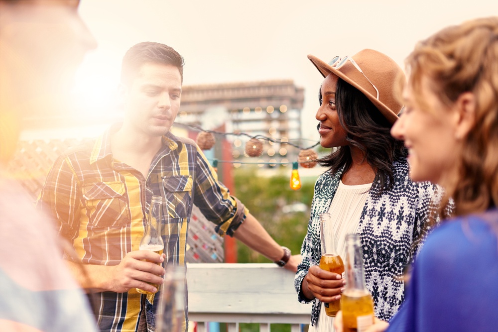 Multi-ethnic millenial group of friends partying and enjoying a beer on rooftop terrasse at sunset.jpeg