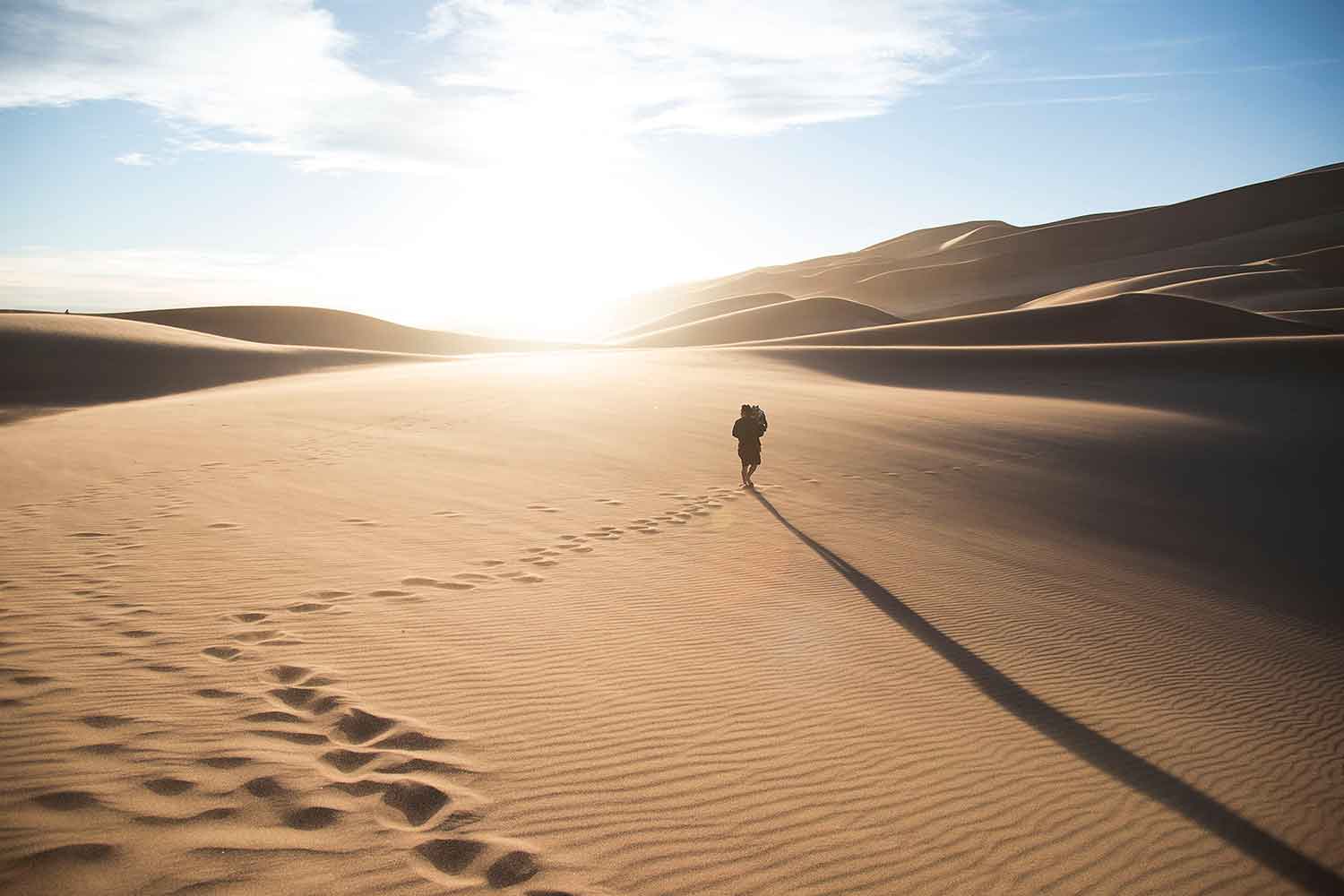man-walking-through-sand-dunes