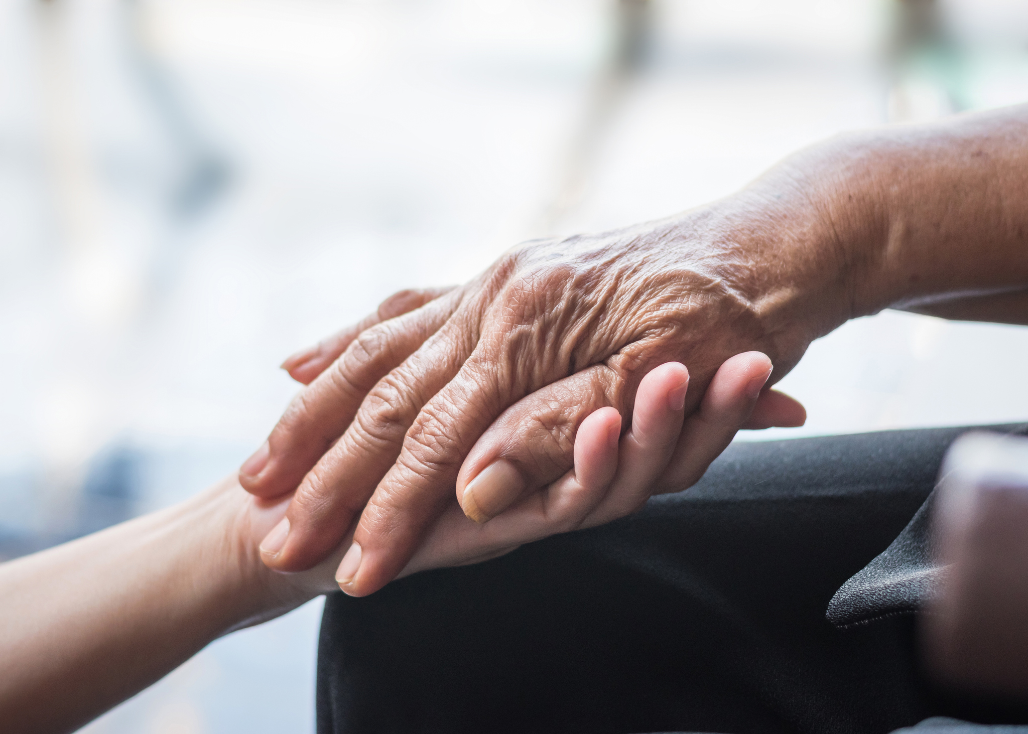 An elderly patients hand being held