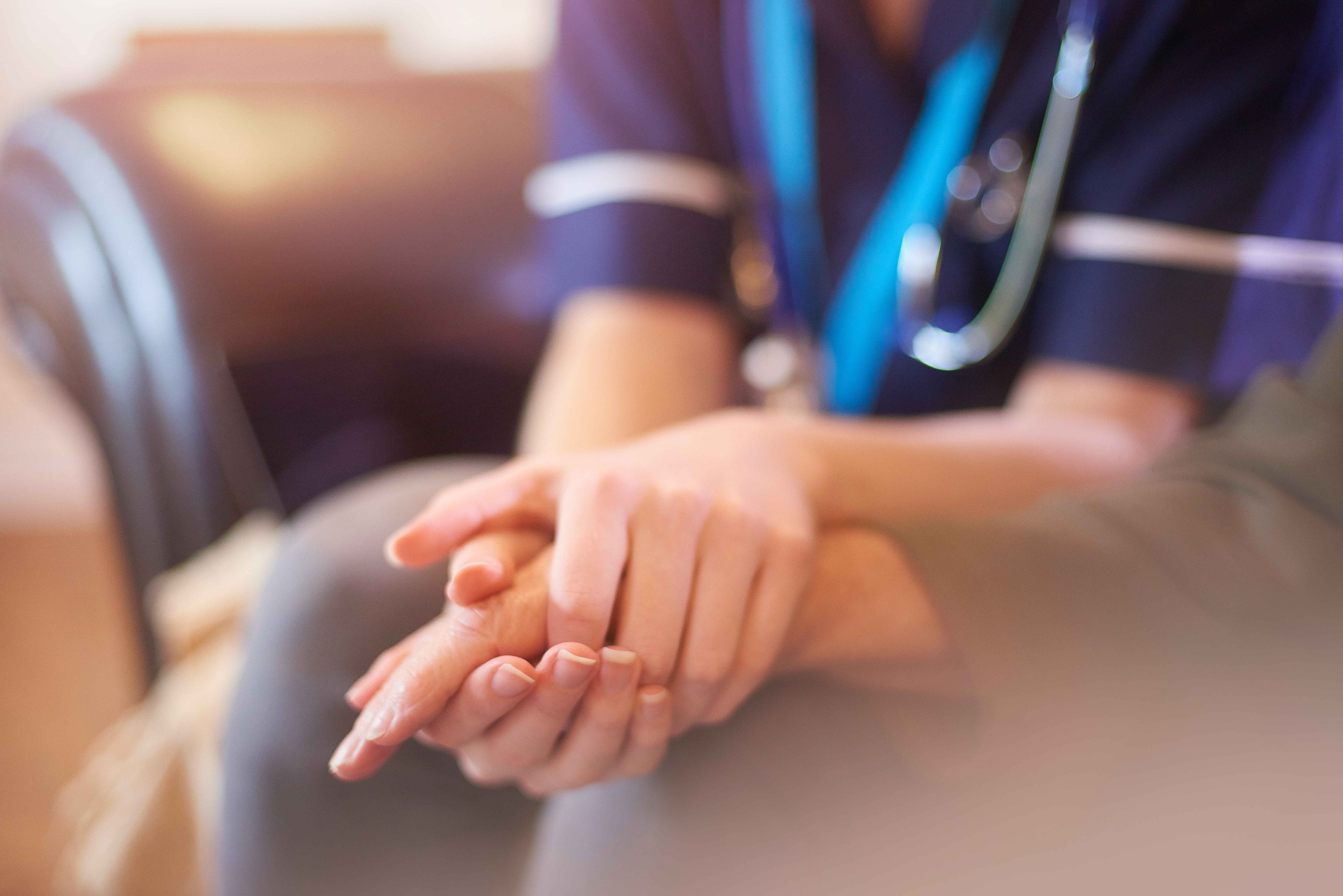 A nurse holding a palliative care patients hand