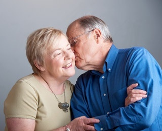 an older gentleman giving his wife a kiss on the cheek