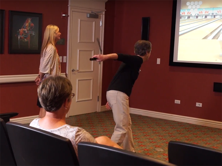  Woman resident playing a virtual bowling game in the theatre. 