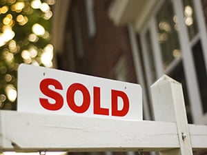 Sold sign sitting in the yard in front of a home