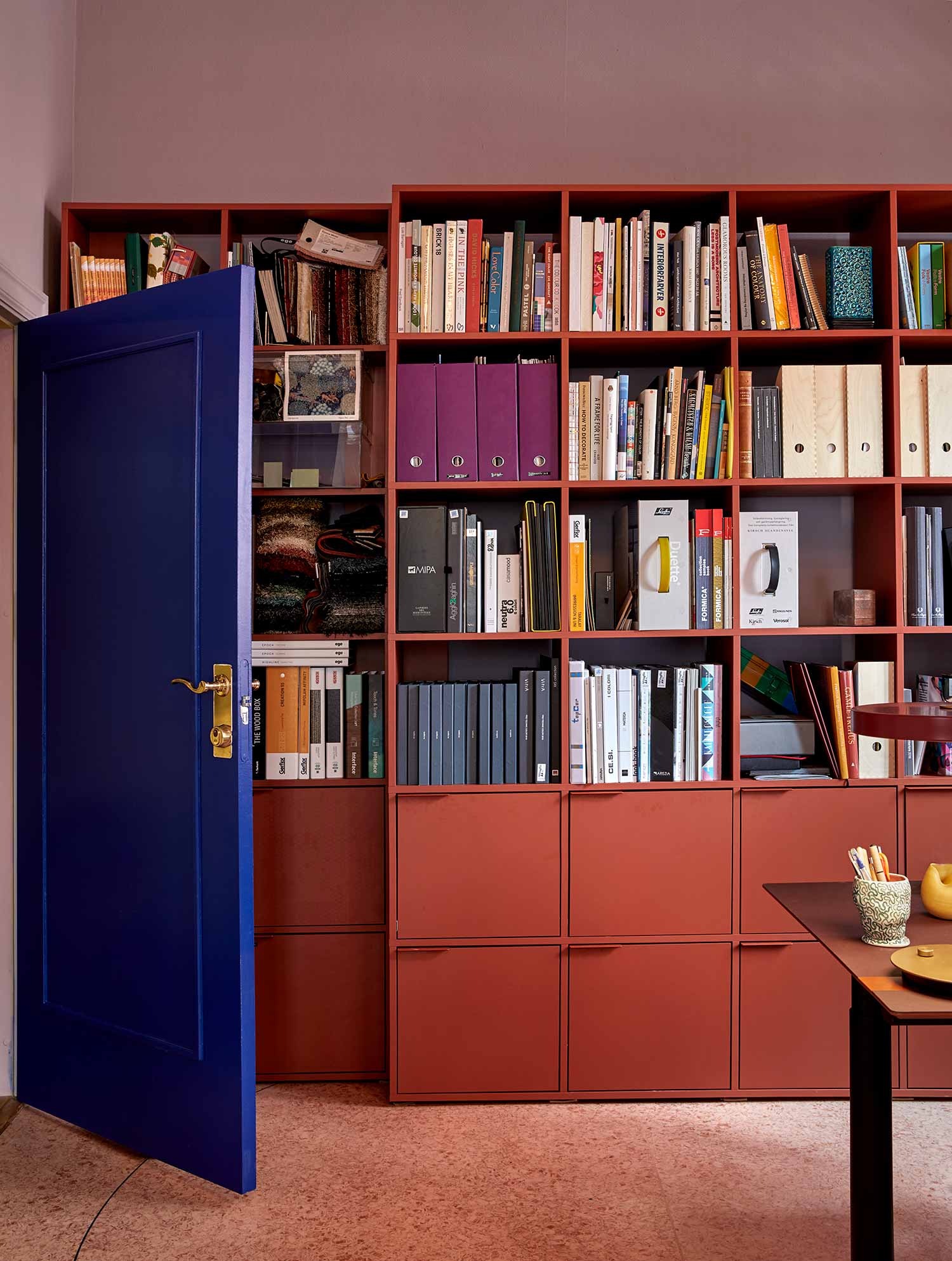 interior of Koi Colour Studios with blue door and large bookcase on the wall