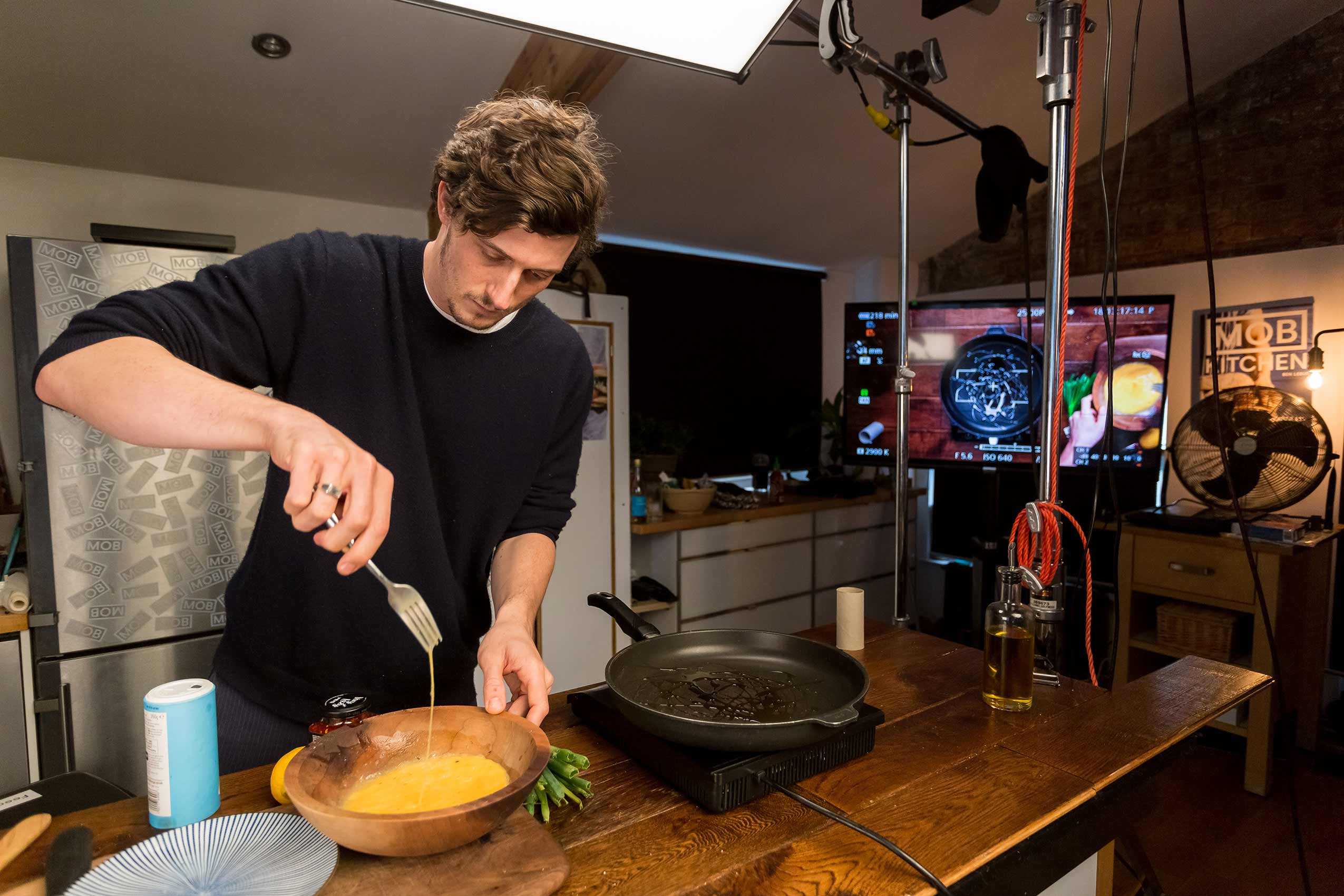 Mob Kitchen founder Ben Lebus scrambling eggs with a fork in a wooden bowl in his office kitchen 