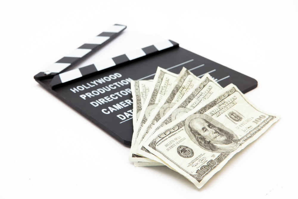 Film slate and money lying against white background.jpeg