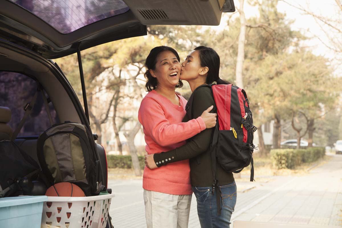 Daughter kissing mom on cheek during college drop off