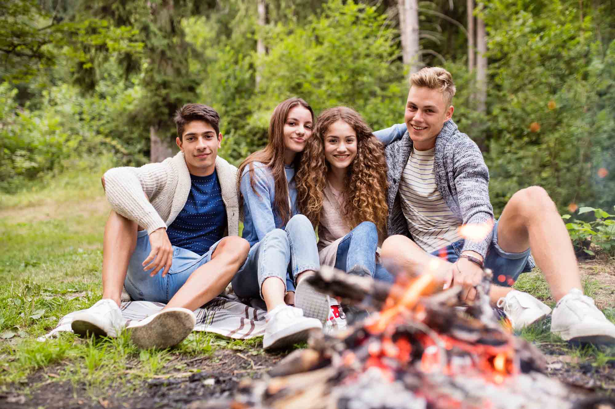 Group of teenagers sitting by campfire.