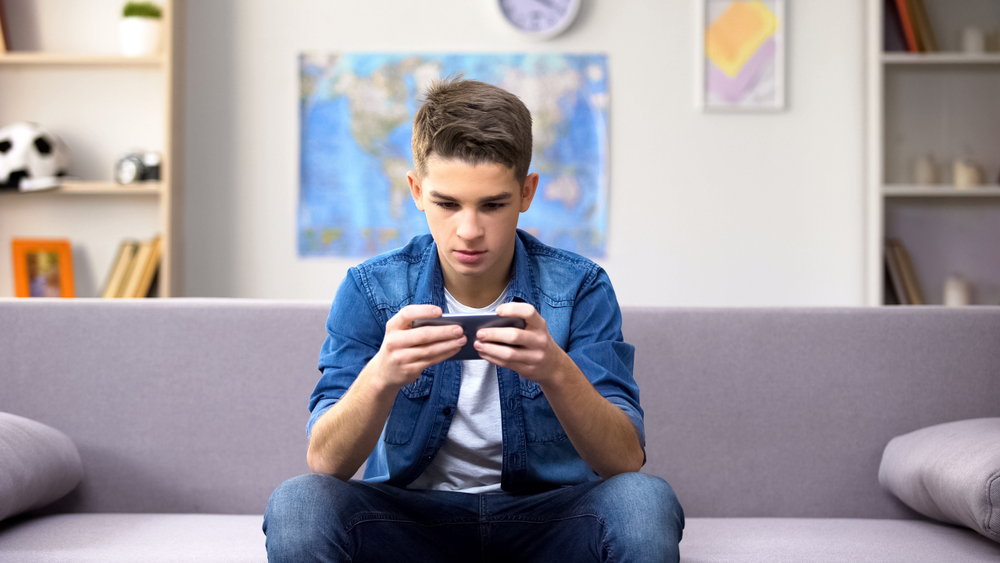 Garoto viciado no celular que ilustra como o uso da internet por adolescentes pode estar sendo mal feito