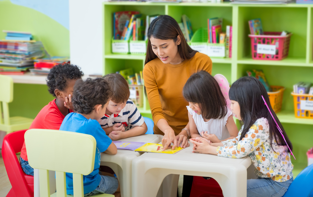 Crianças realizando atividades na pré-escola sob observação de uma professora