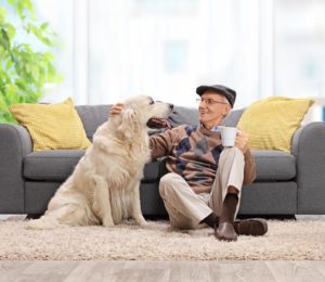 Elderly man sitting on the floor and petting his dog