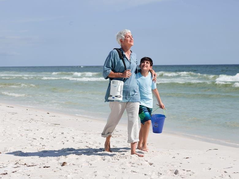 Woman walking on the beach with her grandson.