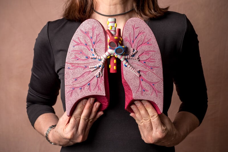 Woman holding lung diagram to her chest.