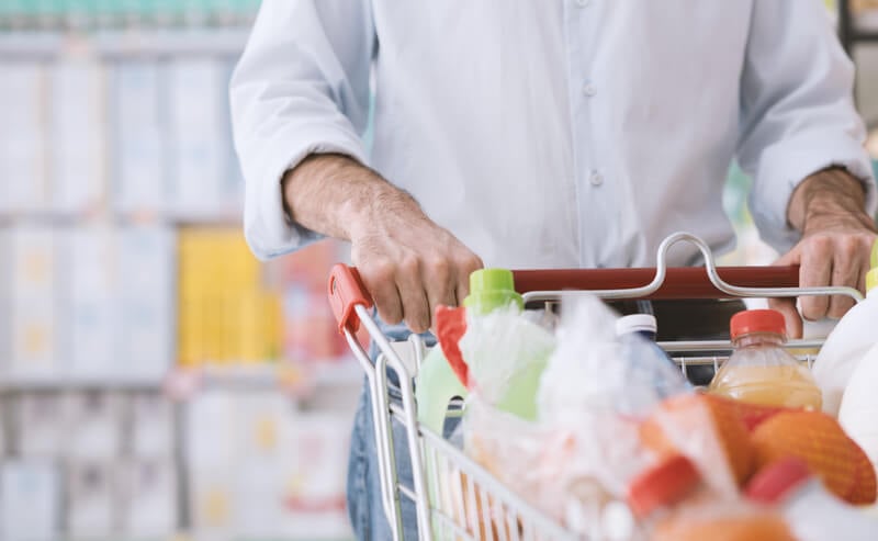 Man pushing shopping cart in a grocery store.