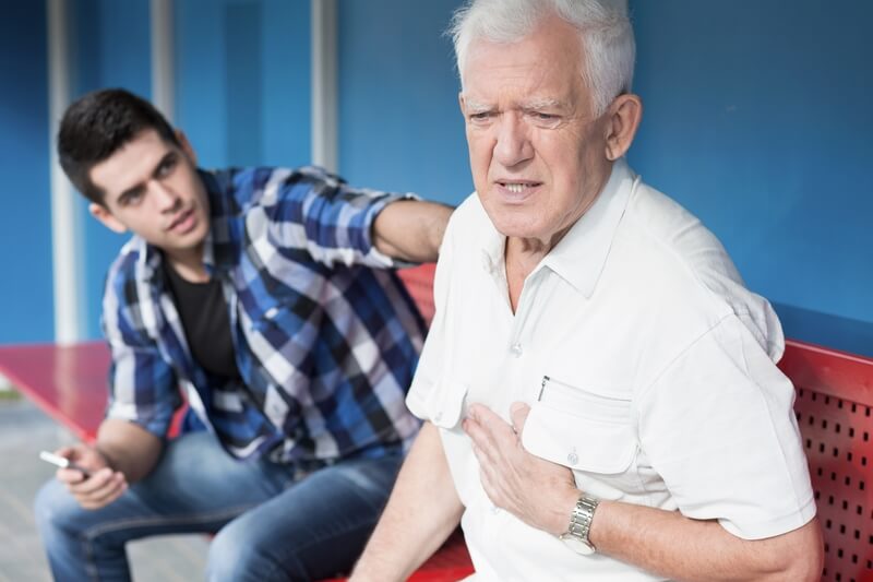Man holding chest while young man touches his shoulder.