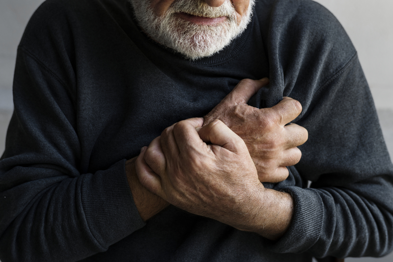 Elderly man holding his chest.