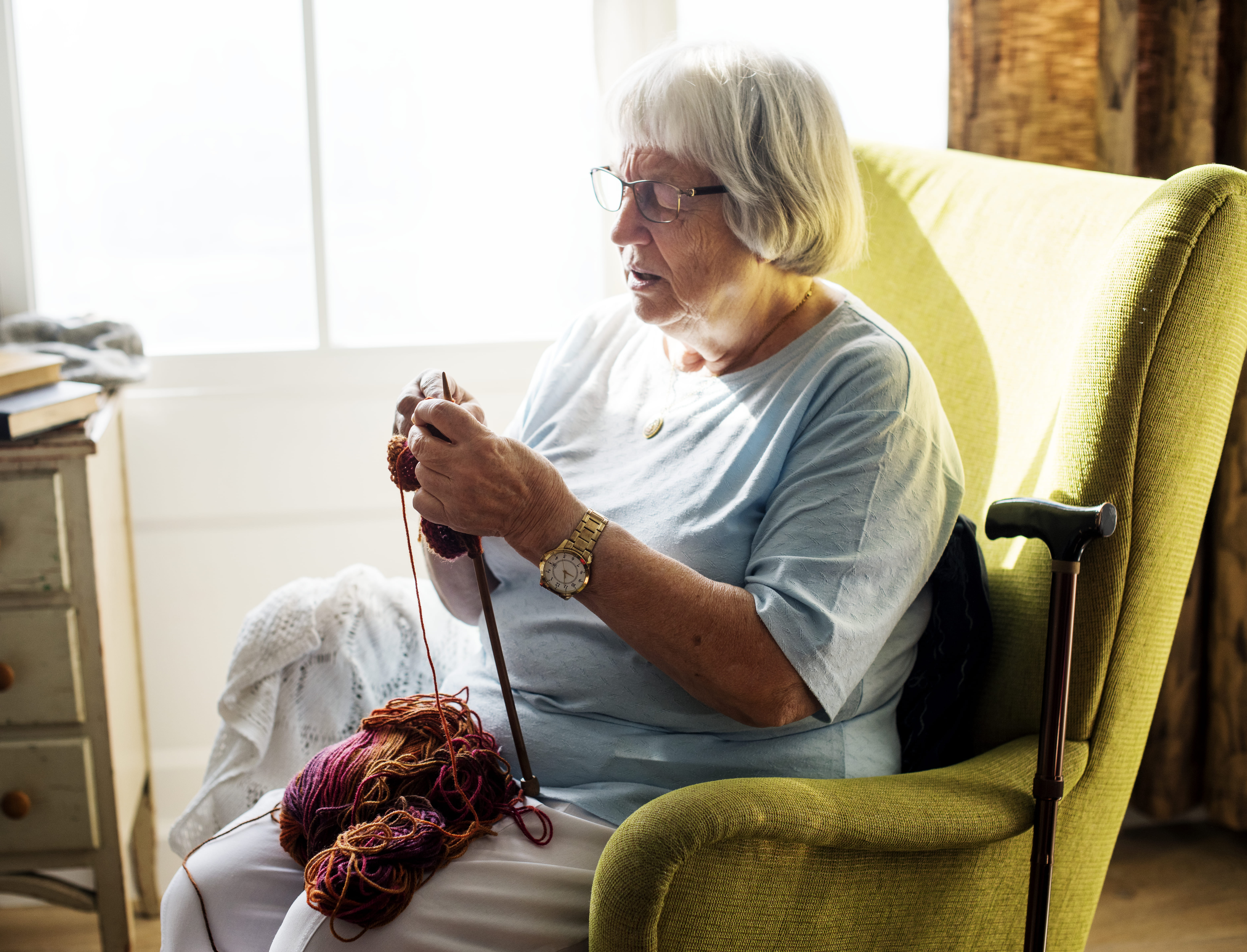 Woman sitting in a chair knitting.