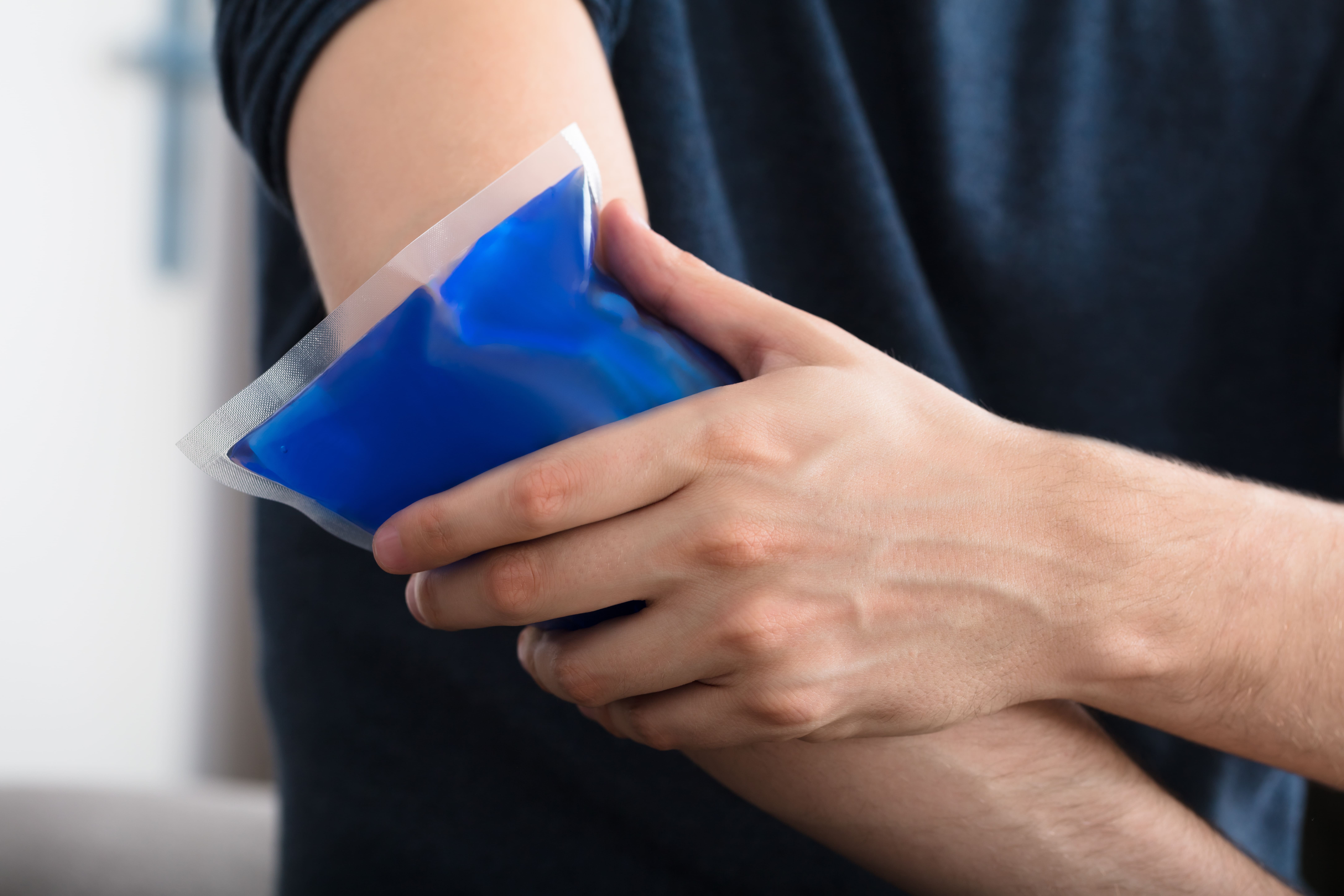 Man applying ice pack to his arm.