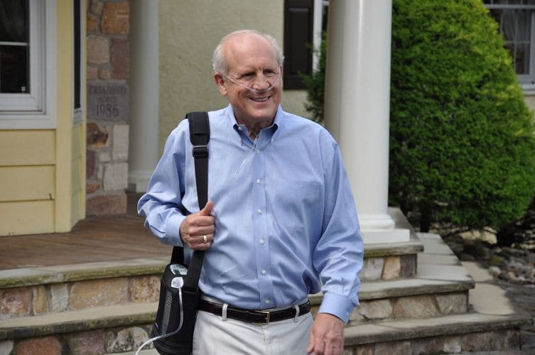Man walking with his portable oxygen concentrator.